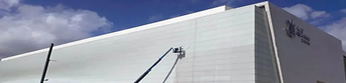Equipe realizando a limpeza da fachada de um edifício com plataforma elevatória