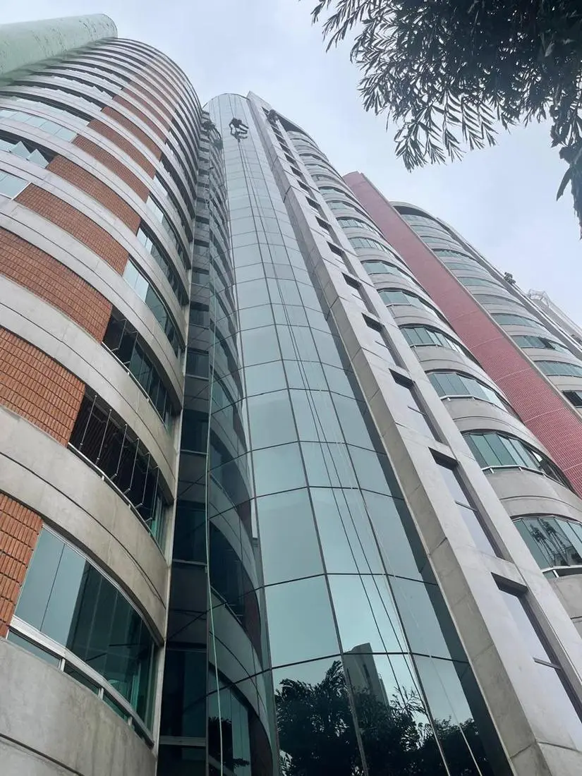 Torre de vidro curvo com profissionais em corda
