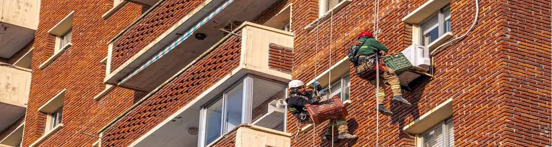 Profissionais em corda trabalhando na vedação de janelas e esquadrias de um edifício